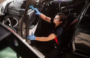 A Safelite technician wearing gloves replacing a vehicle’s power windows