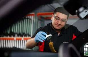 A Safelite technician wearing gloves repairing a windshield
