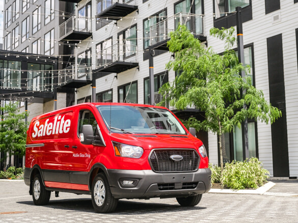 Foto de una furgoneta de Safelite estacionada junto a un edificio residencial.