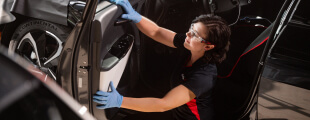 A Safelite technician wearing gloves replacing a vehicle's power windows