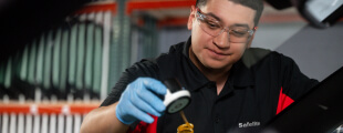 A Safelite technician wearing gloves repairing a windshield