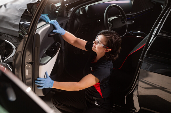 A Safelite technician wearing gloves replacing a vehicle's power windows